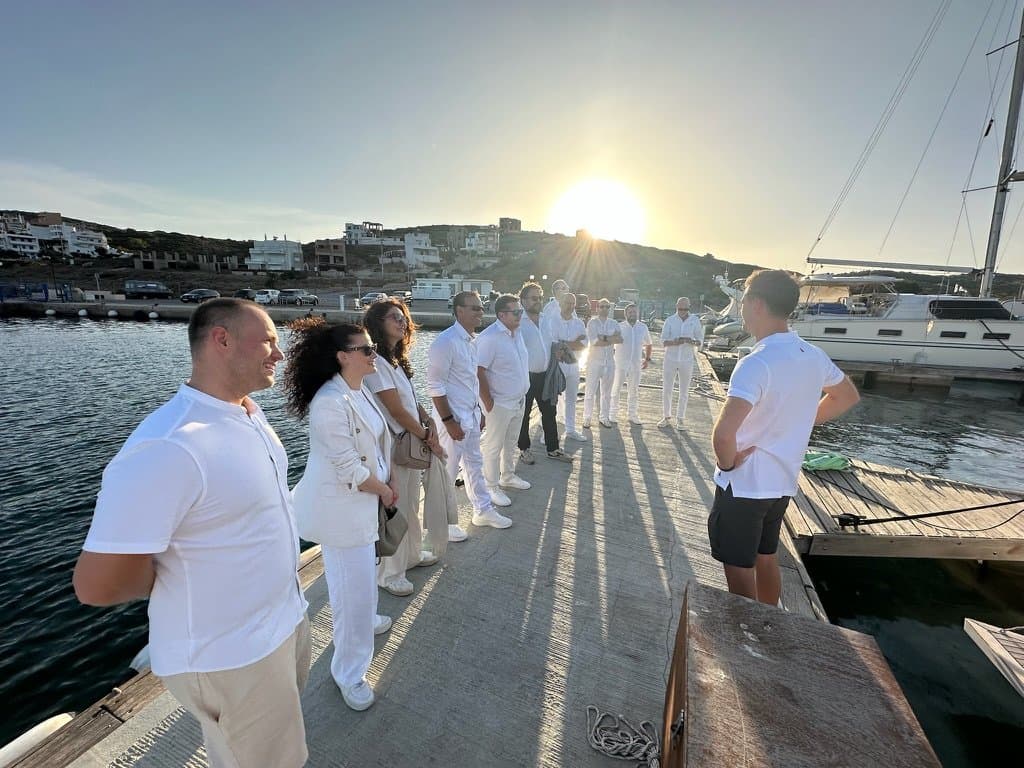 The leadership cohort dressed in white on the dock at sunset before the sailing activity
