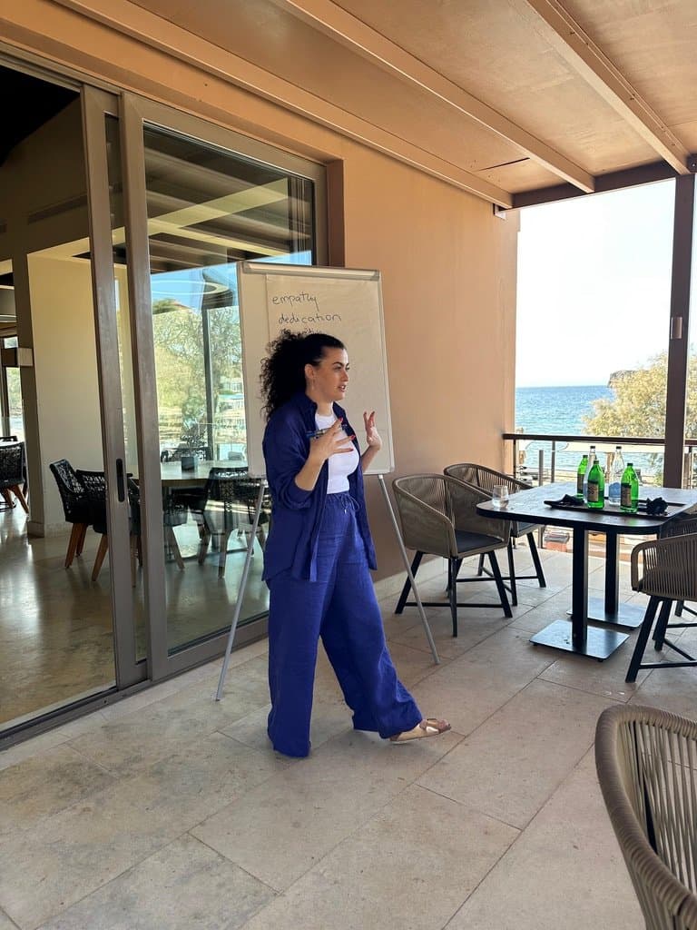 Noam facilitating an outdoor leadership offsite by the sea, whiteboard reading empathy and dedication