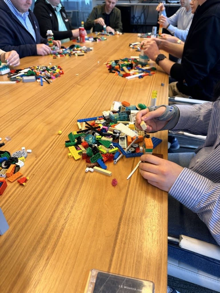 A boardroom table covered in colourful LEGO® bricks, a session in progress