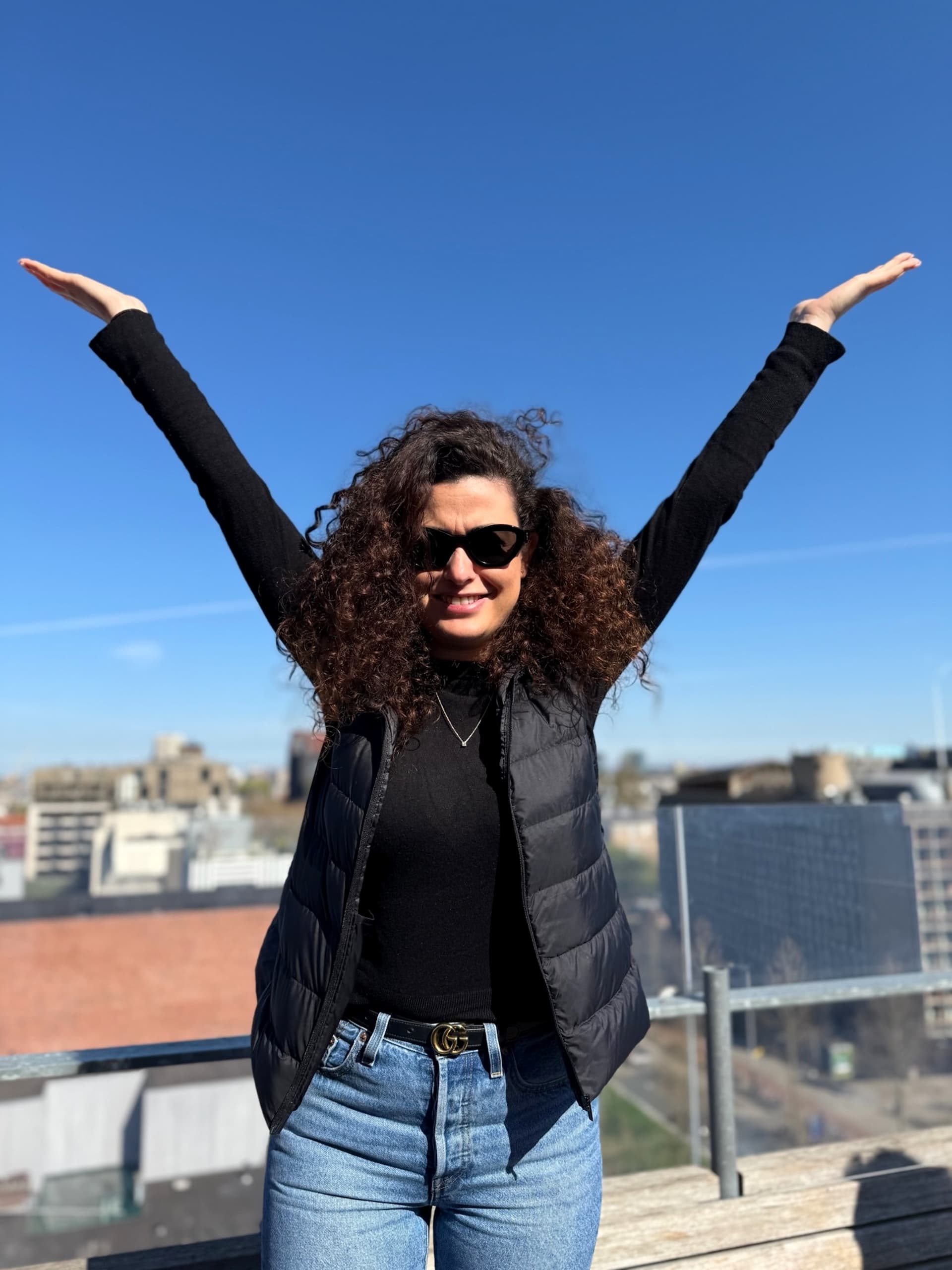 Noam Yossef off the clock, arms up on a rooftop at golden hour